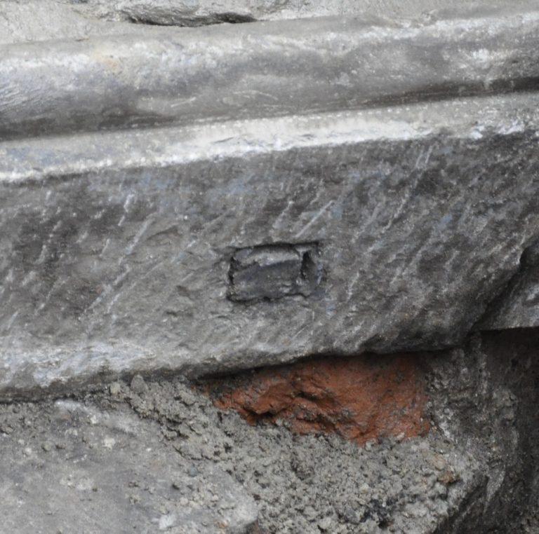 Foto van de onderkant van het zandsteenfragment met restant van een rechthoekige dook van de vroegere bevestiging.